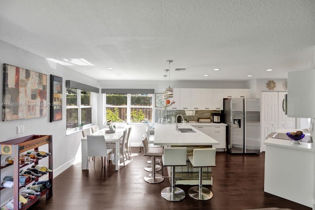 kitchen featuring stainless steel fridge, dark hardwood / wood-style flooring, hanging light fixtures, sink, and white cabinetry