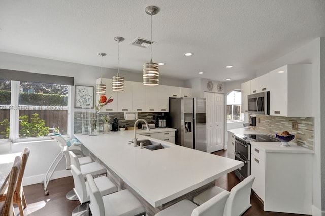 kitchen featuring sink, dark wood-type flooring, a breakfast bar, appliances with stainless steel finishes, and white cabinets