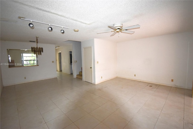 spare room with a textured ceiling, stairway, a ceiling fan, and baseboards