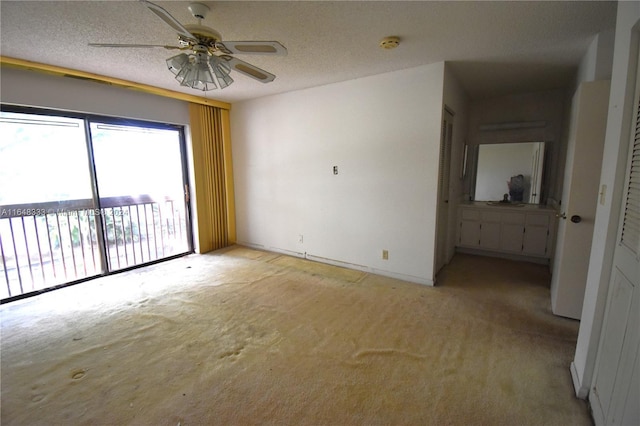 unfurnished room featuring a textured ceiling, light carpet, and a ceiling fan