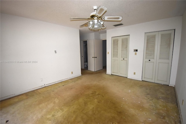 unfurnished bedroom with concrete flooring, a textured ceiling, visible vents, and multiple closets