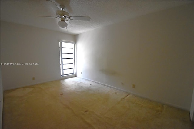 empty room with a textured ceiling, ceiling fan, carpet floors, and baseboards