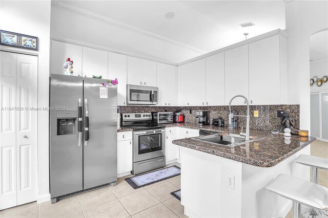 kitchen with tasteful backsplash, stainless steel appliances, kitchen peninsula, sink, and a breakfast bar area