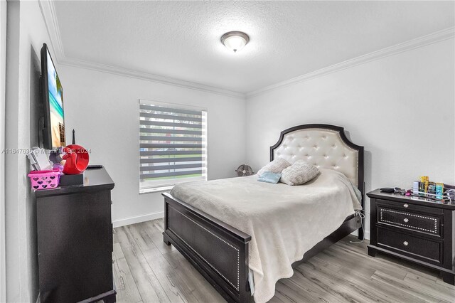 bedroom with a textured ceiling, crown molding, and hardwood / wood-style flooring