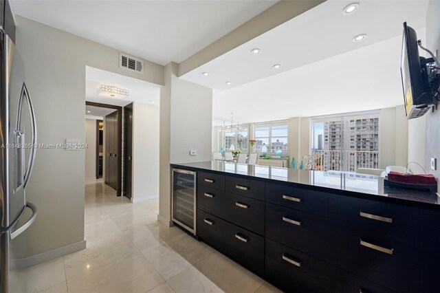 kitchen featuring visible vents, modern cabinets, freestanding refrigerator, dark cabinets, and wine cooler