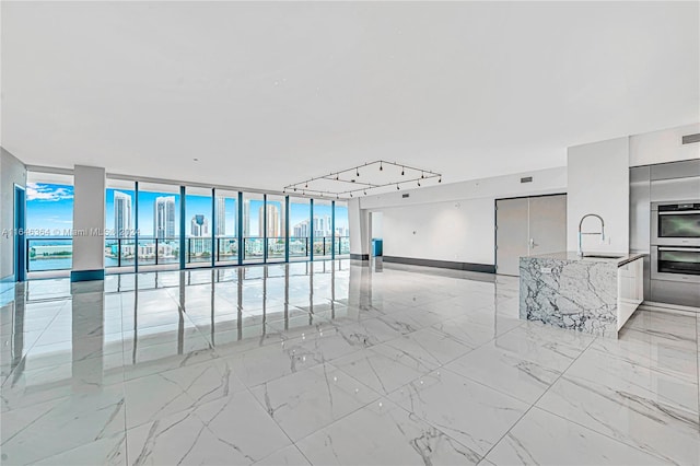 unfurnished room featuring floor to ceiling windows, sink, and track lighting