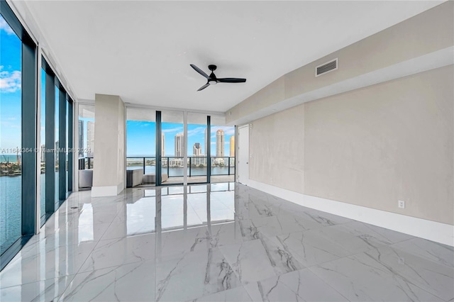 empty room featuring a wall of windows, a water view, and ceiling fan