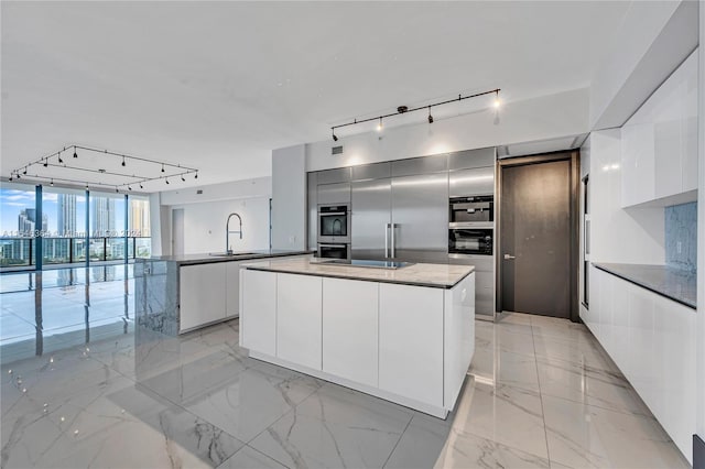 kitchen with sink, track lighting, double oven, a center island, and white cabinets