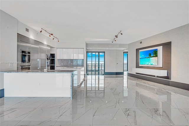 kitchen with white cabinets, rail lighting, and dark stone counters