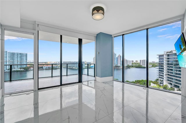 unfurnished room featuring a wealth of natural light, a water view, and floor to ceiling windows