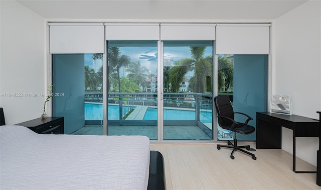 bedroom featuring light wood-type flooring, access to outside, and floor to ceiling windows