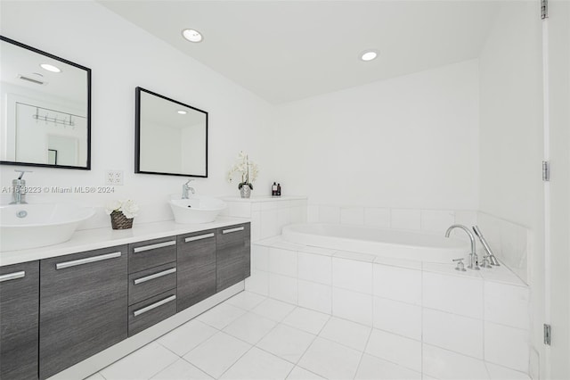 bathroom with tiled tub, tile patterned flooring, and vanity