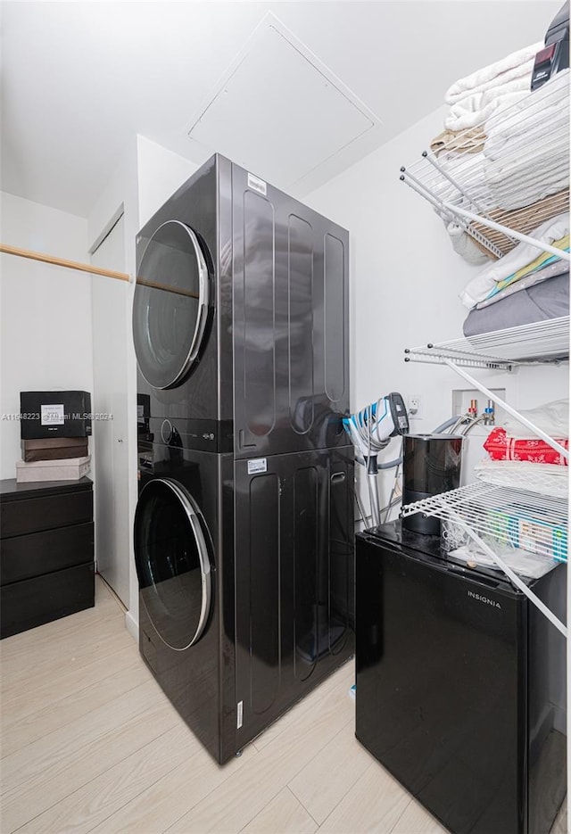 washroom with light hardwood / wood-style floors and stacked washer / dryer