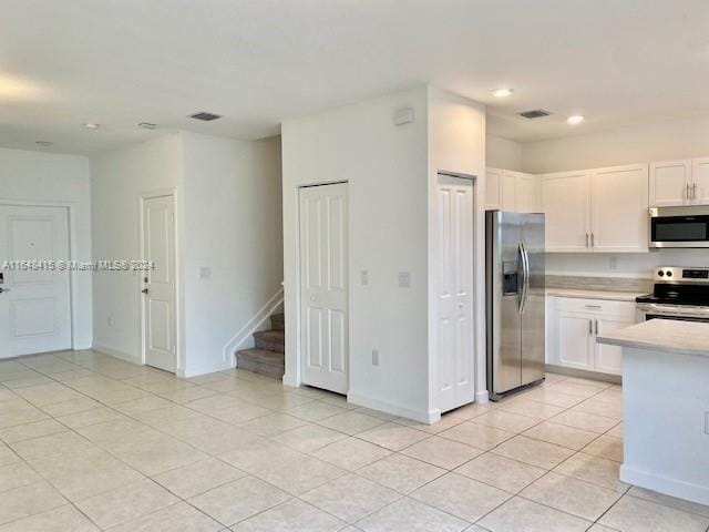 kitchen with light tile patterned flooring, stainless steel appliances, and white cabinetry