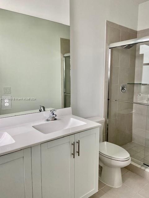 bathroom with tile patterned flooring, vanity, walk in shower, and toilet