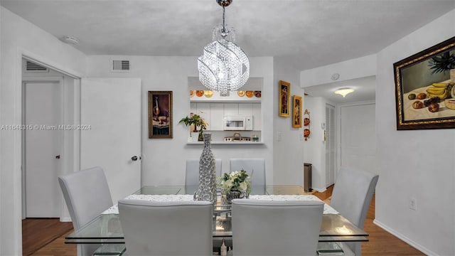 dining room with hardwood / wood-style flooring and a notable chandelier