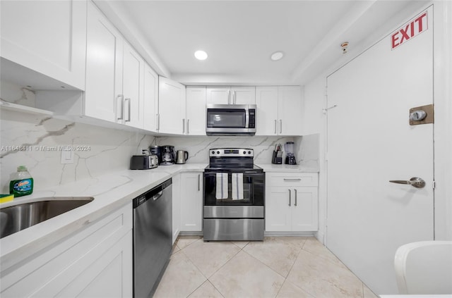 kitchen with backsplash, white cabinets, and appliances with stainless steel finishes