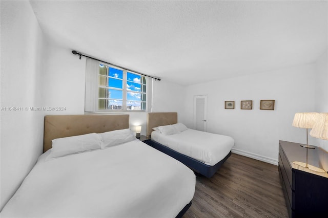 bedroom with a textured ceiling and dark hardwood / wood-style floors