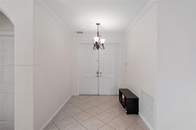 tiled entryway featuring ornamental molding and a notable chandelier