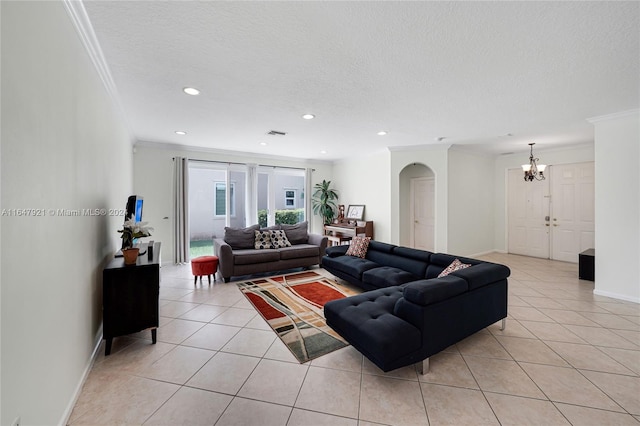 living room with a textured ceiling, ornamental molding, light tile patterned flooring, and a chandelier