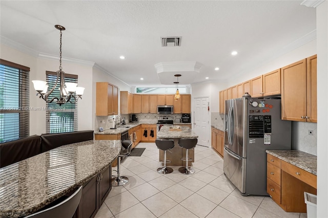 kitchen with pendant lighting, dark stone counters, a center island, an inviting chandelier, and stainless steel appliances