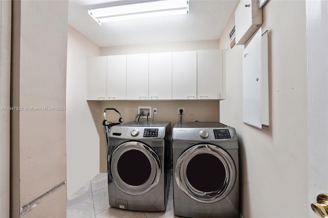 clothes washing area with separate washer and dryer, light tile patterned floors, and cabinets