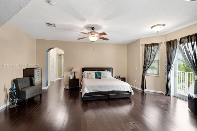 bedroom featuring ceiling fan, a textured ceiling, dark hardwood / wood-style floors, and access to exterior