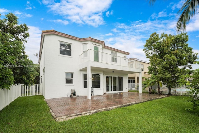 back of house featuring a balcony, a lawn, and a patio