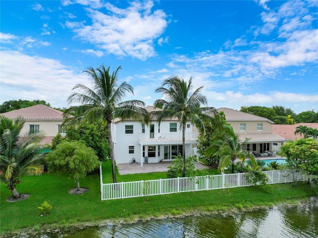 rear view of house with a pool, a yard, a water view, and a patio area