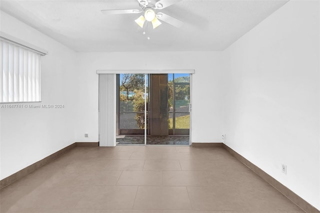 empty room featuring ceiling fan, light tile patterned flooring, and a textured ceiling