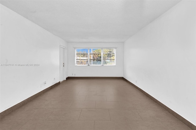 spare room with tile patterned floors and a textured ceiling