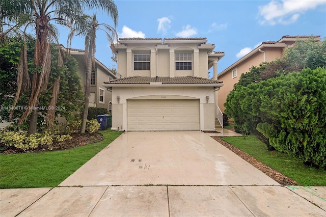 mediterranean / spanish-style house featuring stucco siding, a front lawn, driveway, a garage, and a tiled roof