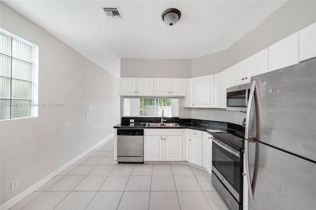 kitchen with appliances with stainless steel finishes, light tile patterned floors, sink, and white cabinets