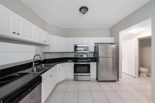 kitchen with appliances with stainless steel finishes, white cabinetry, light tile patterned floors, and sink