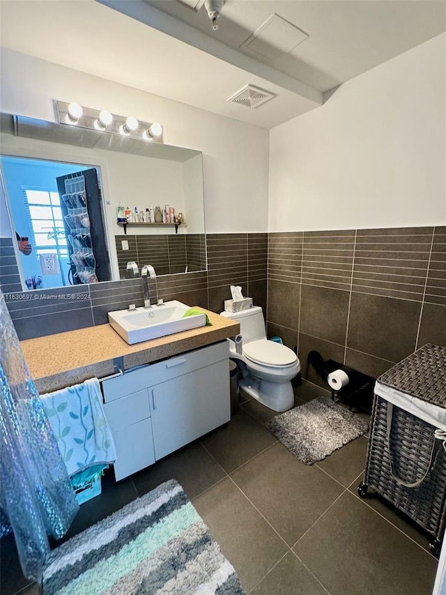 bathroom with toilet, vanity, tile walls, and tile patterned floors