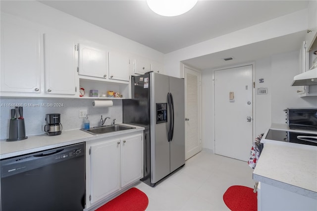 kitchen with light tile patterned flooring, black dishwasher, sink, white cabinetry, and stainless steel fridge