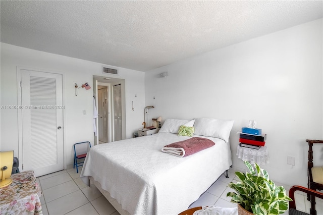 tiled bedroom featuring a textured ceiling