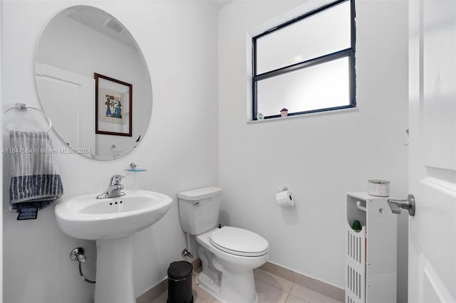 bathroom with baseboards, tile patterned flooring, a sink, and toilet