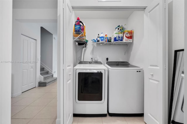 laundry area featuring washing machine and dryer, light tile patterned floors, and laundry area