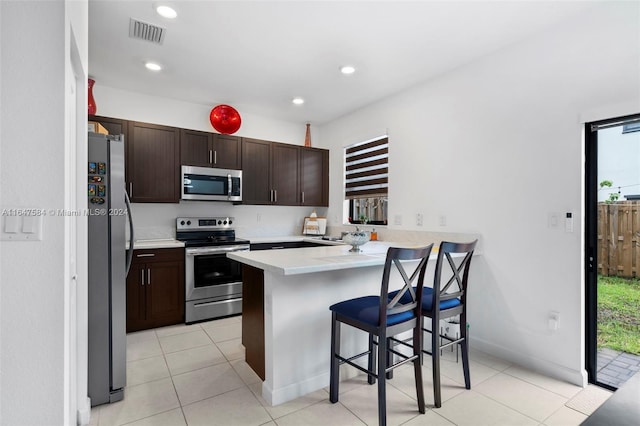 kitchen featuring stainless steel appliances, a peninsula, light countertops, visible vents, and a breakfast bar