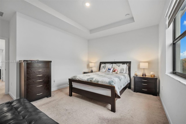 bedroom featuring baseboards, a raised ceiling, and light colored carpet