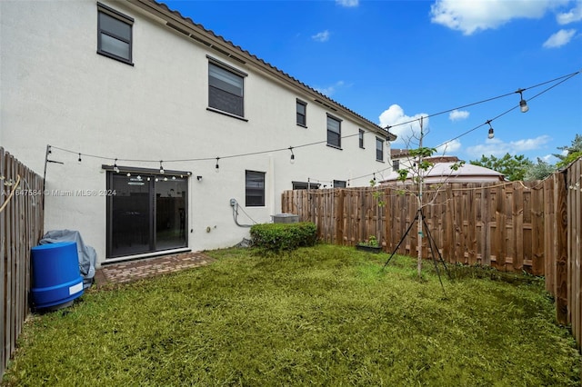 back of house featuring stucco siding, a yard, and a fenced backyard