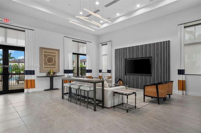 tiled living room featuring an inviting chandelier and a tray ceiling