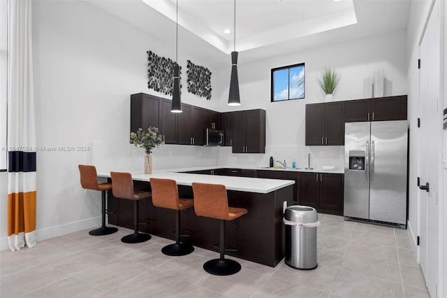 kitchen featuring a raised ceiling, stainless steel appliances, kitchen peninsula, and a kitchen bar