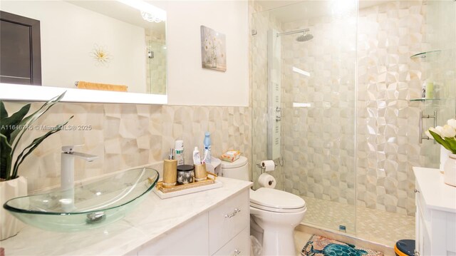 bathroom featuring vanity, toilet, tile walls, and walk in shower