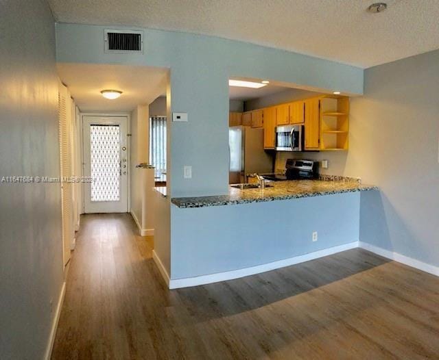 kitchen with kitchen peninsula, stainless steel appliances, dark wood-type flooring, and a textured ceiling