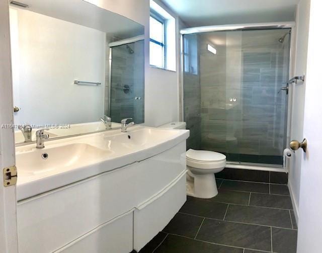 bathroom with tile patterned flooring, an enclosed shower, toilet, and vanity