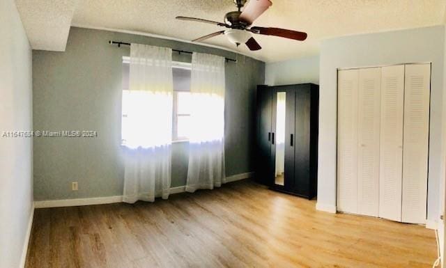 unfurnished bedroom with light wood-type flooring, ceiling fan, a closet, and a textured ceiling