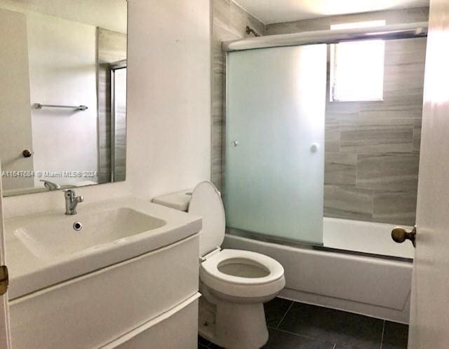 full bathroom featuring combined bath / shower with glass door, tile patterned floors, vanity, and toilet