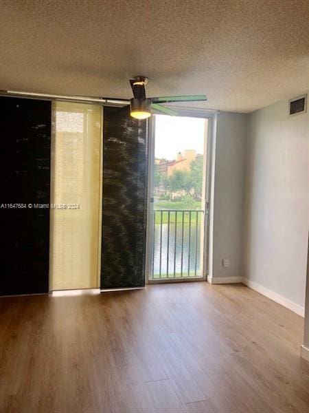 spare room with ceiling fan, hardwood / wood-style flooring, a textured ceiling, and floor to ceiling windows